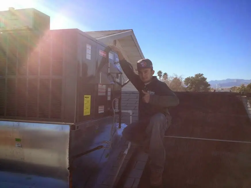 HVAC technician performing AC Tune-Up on a rooftop unit in Benson